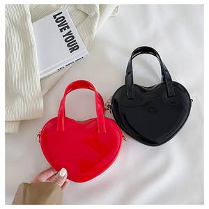 Detail of red and black heart-shaped handbags with glossy finish and gold chain decor