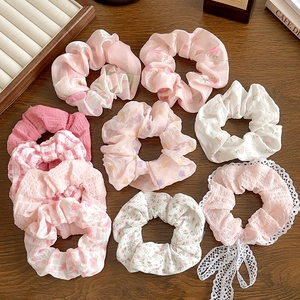 Floral and lace scrunchies collection in pink and white on a wooden background