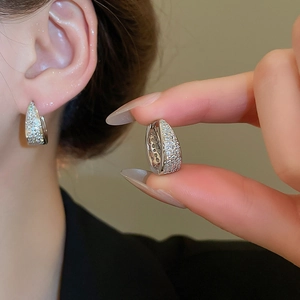 Detailed view of silver U-shaped hoop earrings with zircon crystals on model