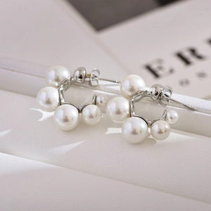 Macro shot of curved pearl earrings with small pearls on a silver metal base