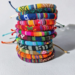 Close-up of stacked bohemian hand-woven surf bracelets with colorful ethnic patterns