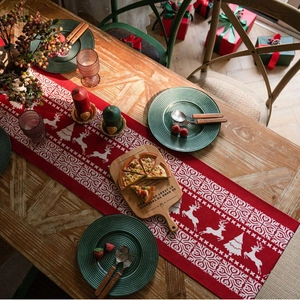 Red Christmas table runner with white reindeer jacquard pattern on wooden dining table