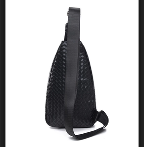 Detail view of the black woven leather chest bag showing the nylon strap and metal buckle