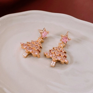 Macro view of Christmas tree earrings with pink crystals on gold metal tray