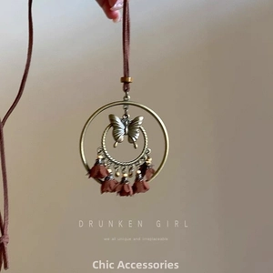 Gros plan d'un anneau en bronze avec pendentif papillon 3D et pompons marrons