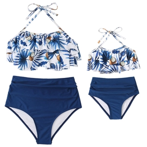 Flat lay of matching mother and daughter swimwear with tropical palm print and ruffles