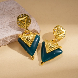 Détail de boucles d'oreilles triangulaires en résine rétro avec strass sur socle en pierre