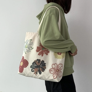 Floral canvas tote bag detail showing hand-painted flower prints on creamy white fabric