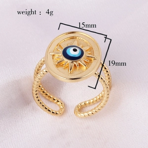 Close-up of sun-shaped evil eye ring showing dimensions on pink silk background
