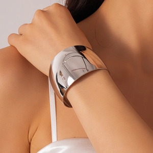 Close-up of a wide polished silver cuff bracelet with a glossy mirror finish on wrist