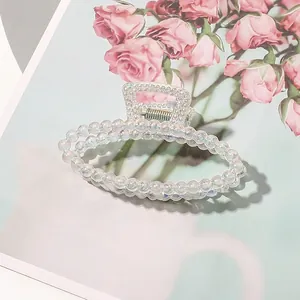 Detail of a large iridescent claw clip with hollow oval frame on a floral background