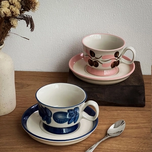 Close-up of vintage hand-painted ceramic coffee cups with floral patterns on wood