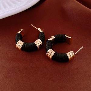 Detailed view of C-shaped gold metal hoop earrings with black faux leather woven texture