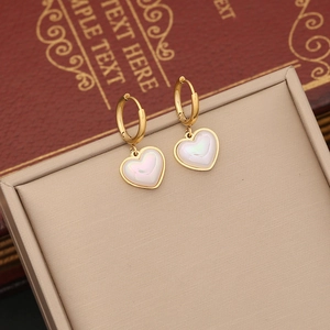 Golden hoop earrings with pearl heart pendants displayed on a vintage book