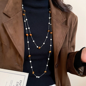 Nahaufnahme der zweilagigen Tigerauge- und Perlenkette getragen auf einem braunen Blazer