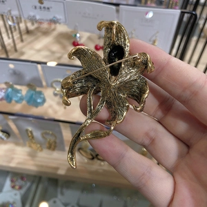 Detail of the vintage gold lily brooch back showing the pin fastener and textured metal finish