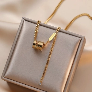 Collier double couche doré avec pendentif cylindrique et strass sur boîte à bijoux