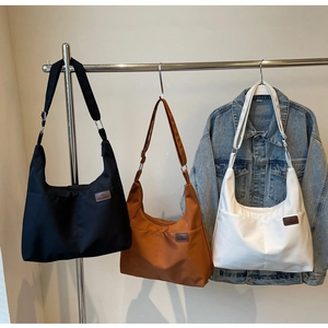 Three minimalist canvas tote bags in black, coffee, and white shown on a display rack