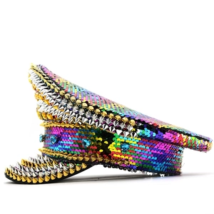 Rainbow sequin captain hat with metallic spikes and blue heart gems on a plain background
