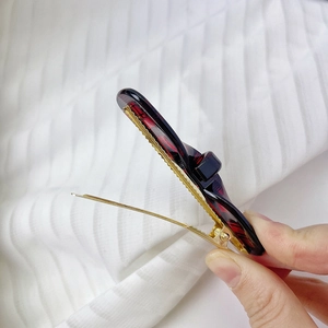 Detail of dark red tortoiseshell bow hair clip with gold metal clamp mechanism