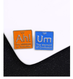 Gros plan de broches en émail du tableau périodique avec les éléments Ah et Um sur un plat