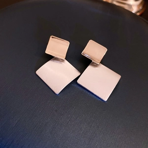 Close-up of geometric brushed metal rhombus earrings in gold and rose gold plating