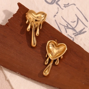 Macro detail of 18K gold plated heart earrings with lava fluid style on dark wood surface