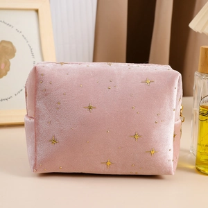 Detail of pink velvet makeup bag featuring gold foil stars and a metallic zipper