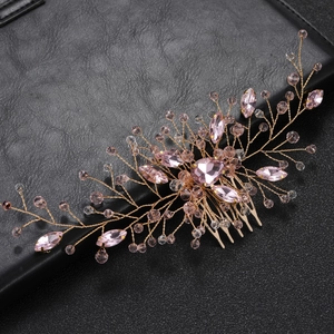 Elegant bridal hair comb with gold wire and pink rhinestones on a textured black surface