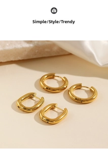 Detailed close-up of golden geometric earrings on elegant beige props with silk