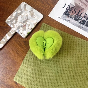 Close-up of heart-shaped green plush hair claw clip on stylish background props
