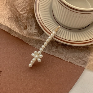 Detail of elegant pearl hair clip with gold metal base and floral accent on brown desk