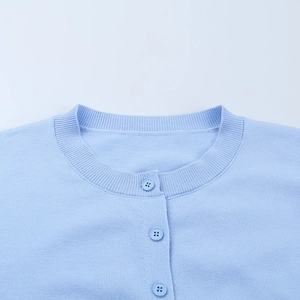 Détail d'un cardigan en maille bleu clair avec col rond et boutons assortis