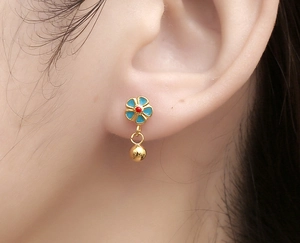 Macro shot of gold floral earrings with light blue enamel and spherical metal pendants