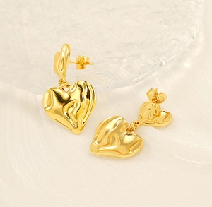 Detailed view of layered gold heart earrings with molten metal texture and glossy finish