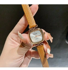 Close-up of elegant square quartz watch with brown leather strap and gold case