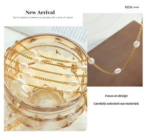 Close-up of golden flat chain necklace with baroque freshwater pearls on wooden surface
