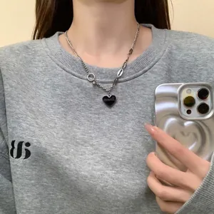 Détail du collier coeur en argent avec émail noir et chaîne asymétrique porté par le modèle