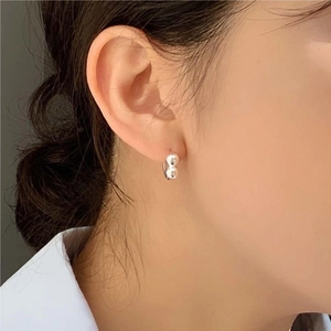 Close-up of minimalist sterling silver hoop earrings with pearls worn by a model