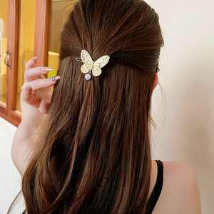 Golden butterfly hair clip with white pearl pendant worn by model on hair side