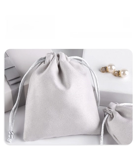 Close-up of soft grey microfiber jewelry pouch with drawstring and elegant pearl earrings