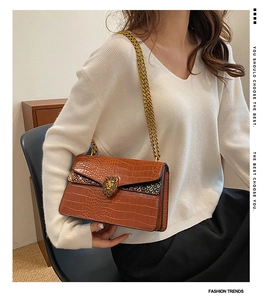 Detail of crocodile pattern leather shoulder bag with gold lion head clasp and chain