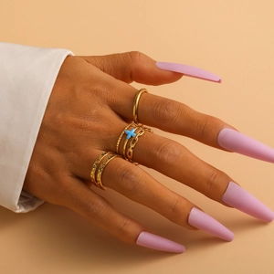Detail of gold titanium steel ring set featuring blue cross charm and textured bands