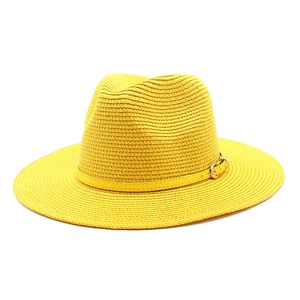 Detail of yellow straw fedora hat featuring woven texture and decorative belt with metal buckle