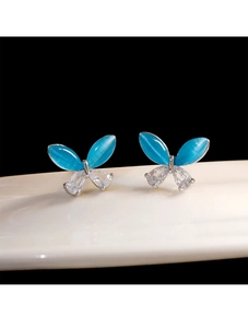 Detail of butterfly stud earrings with blue cat eye stones and sparkling zircons