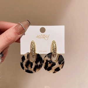 Macro shot of 925 silver post earrings featuring leopard print and gold metal texture