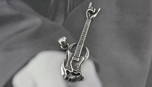 Detailed shot of silver titanium steel guitar pendant with skull and rock hand gesture
