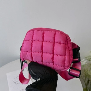 Detail of pink quilted nylon crossbody bag featuring adjustable strap and black buckle closure