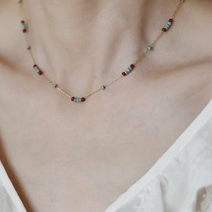 Detail of vintage bohemian choker featuring gold chain with turquoise and burgundy beads
