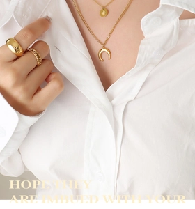 Close-up of gold layered necklace with crescent moon and star pendants with matching rings
